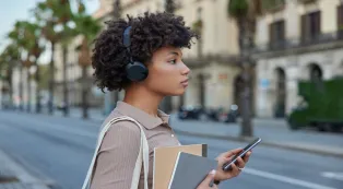 A woman wearing a headphone while walking outdoors