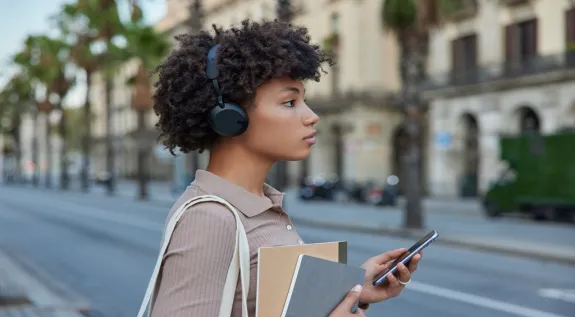 A woman wearing a headphone while walking outdoors