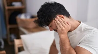 Man covering his ears to illustrate ear discomfort after prolonged headphone use