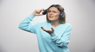 Woman removing her headphones to hear the people around her