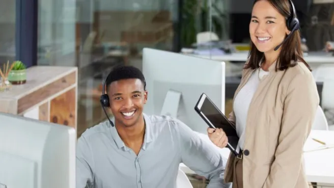 Two bank employees wearing professional wireless headsets with noise-cancelling microphones, working at a banking call center to provide clear customer service.