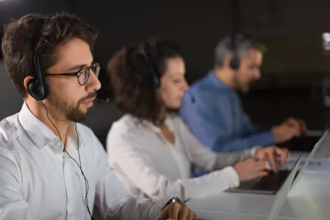Best noise cancelling headset for call center agents: A professional call center agent wearing a Nuroum wireless headset with usb dongle in a modern office environment.