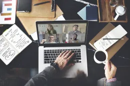 Top-down view of a professional desk setup during an online video conference call, emphasizing the need for a reliable business wireless headset.