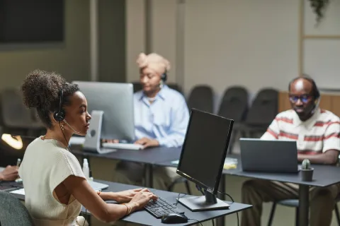 Three staff members with headsets working at computers in a call center office