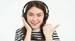 A happy young woman pointing sideways while wearing an over ear wireless noise cancelling headset