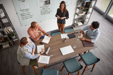 Remote colleague listening to an in-room team discussion during a hybrid meeting
