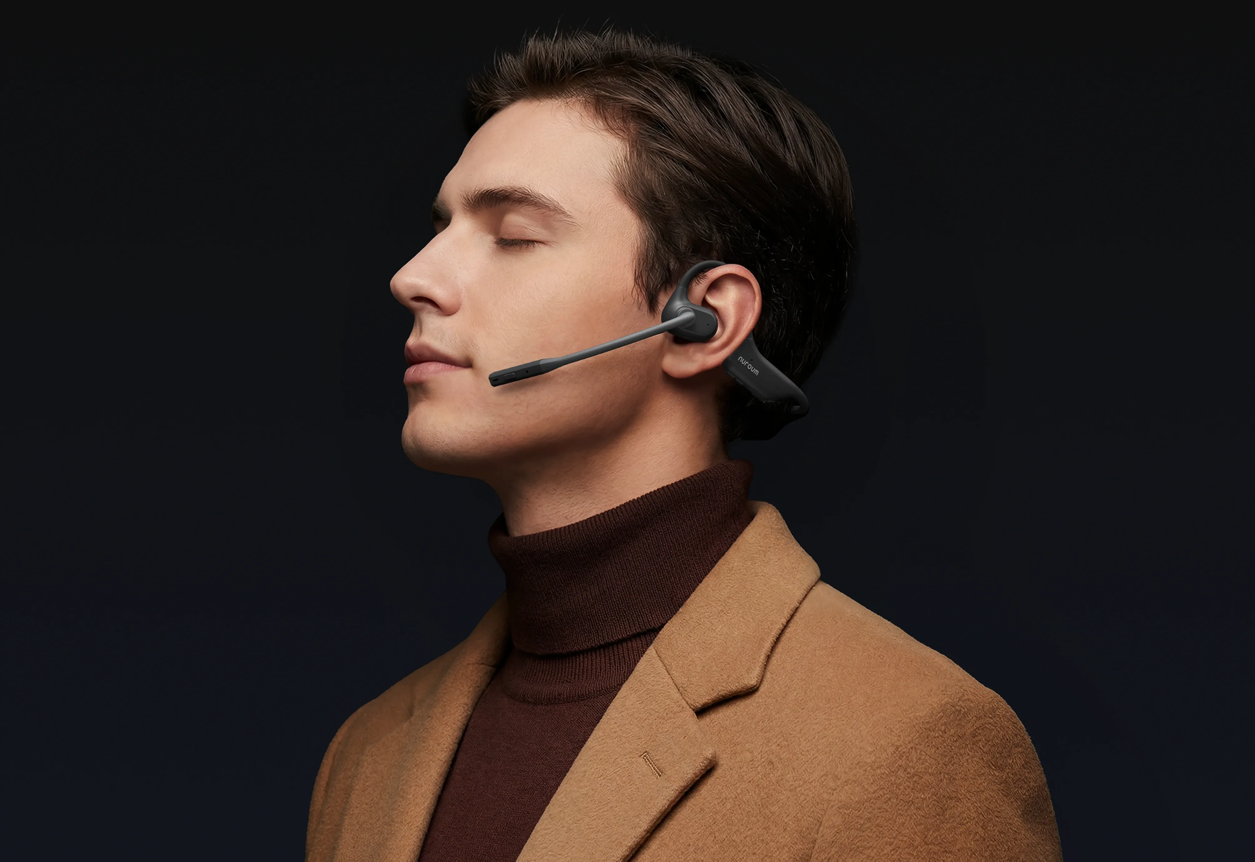 Professional man wearing a Nuroum open-ear wireless headset with boom microphone against a dark background.