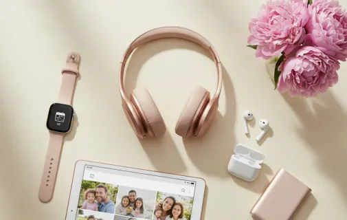 A collection of rose gold tech accessories including a smartwatch and headphones, making them some of the mothers day best gifts.