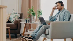 A man wearing closed back headphones working from home at his desk during a video call.